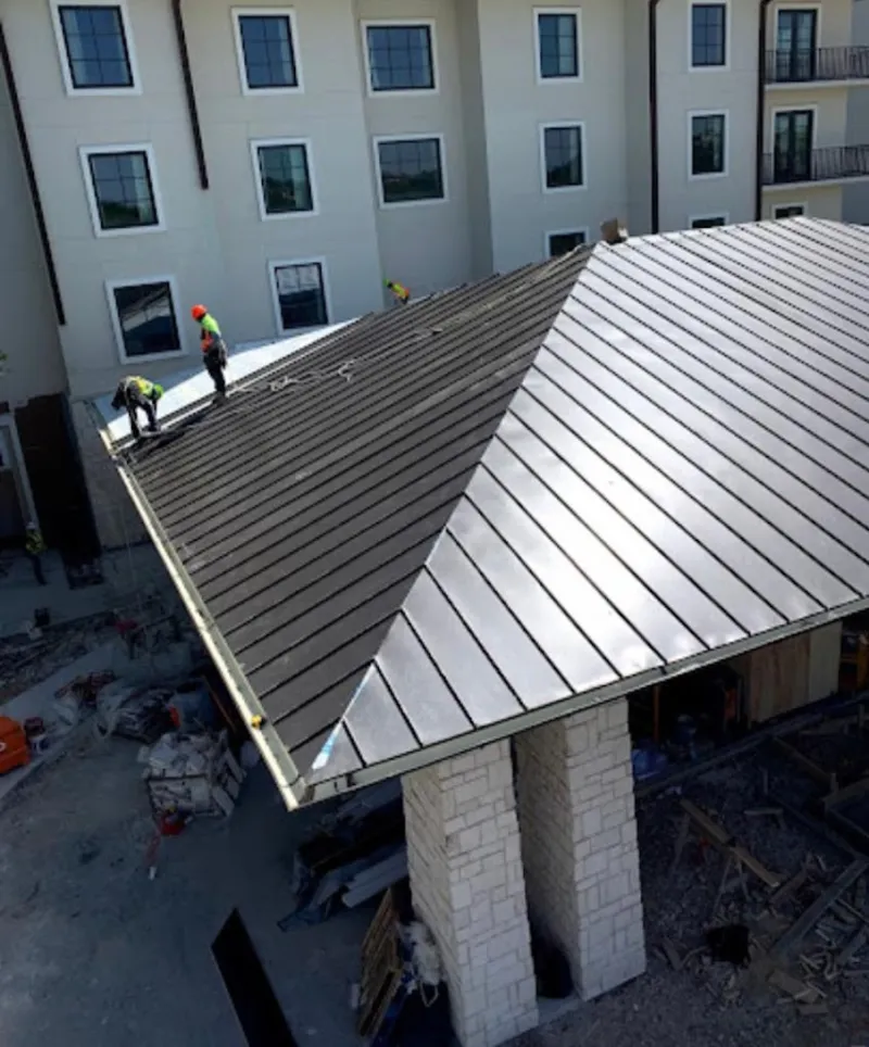 Crew installing standing seam metal roof panels on a commercial project in Port Huron